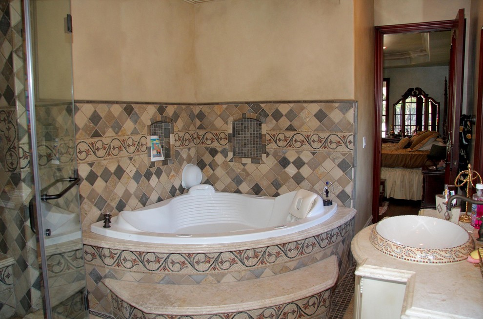Inspiration for a large mediterranean master bathroom in Los Angeles with a hot tub, a corner shower, beige walls, ceramic floors, a drop-in sink, beige floor, a hinged shower door, multi-coloured tile, stone tile and beige benchtops.