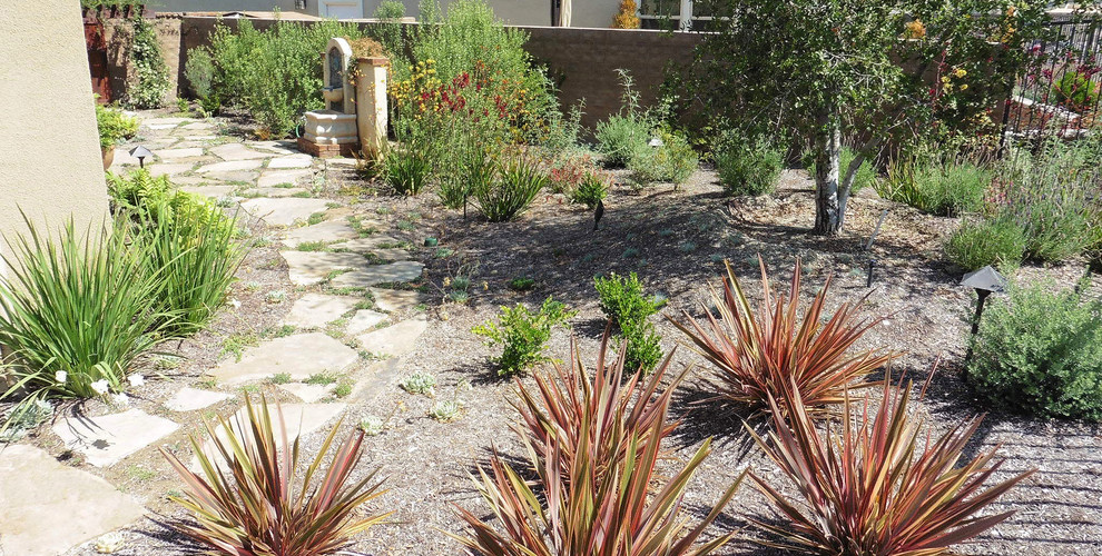 Photo of a large transitional backyard full sun garden for summer in Orange County with natural stone pavers.