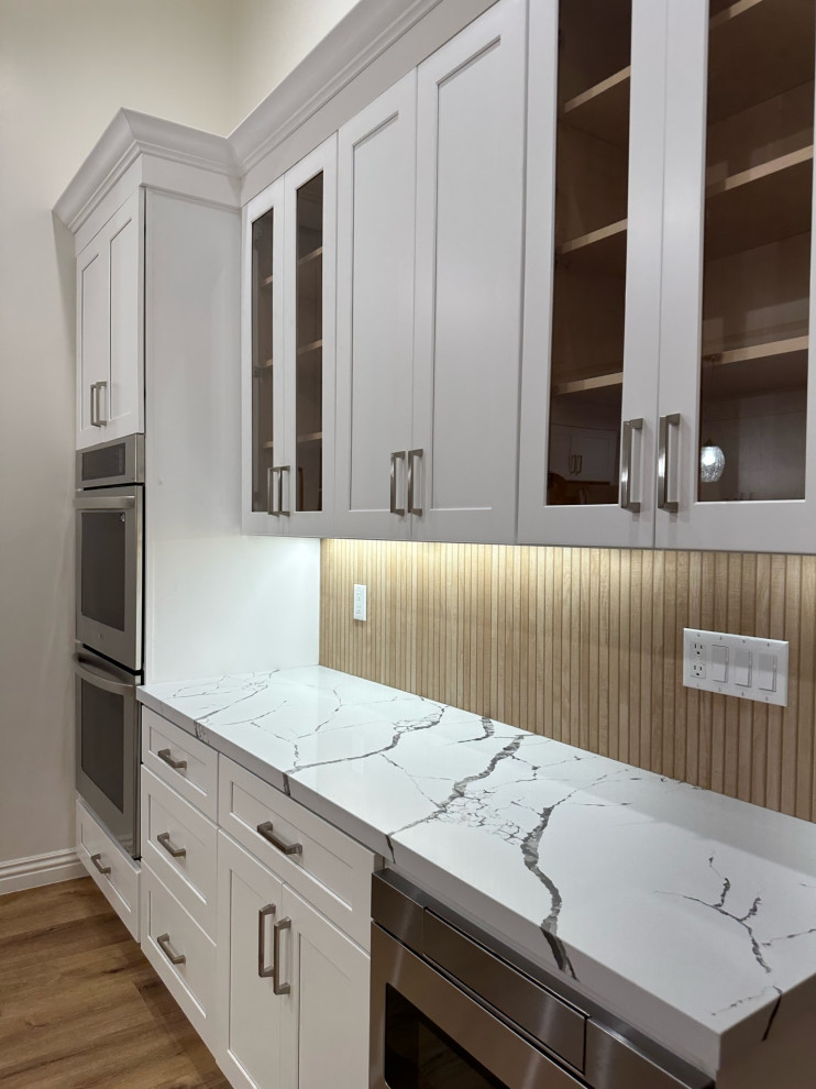 Inspiration for an expansive asian eat-in kitchen in Los Angeles with a farmhouse sink, shaker cabinets, white cabinets, quartzite benchtops, brown splashback, porcelain splashback, stainless steel appliances, dark hardwood floors, with island and white benchtop.