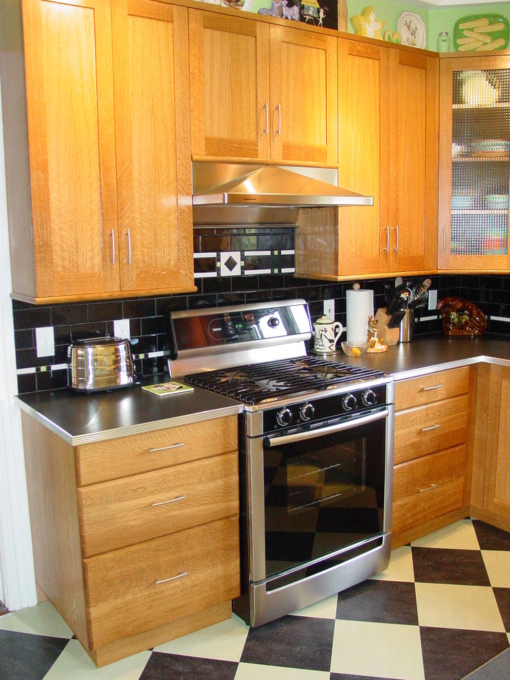 Photo of an arts and crafts u-shaped separate kitchen in Providence with shaker cabinets, light wood cabinets, laminate benchtops, black splashback, subway tile splashback, stainless steel appliances, linoleum floors and with island.