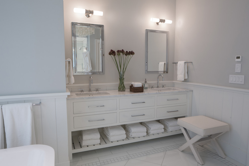 Design ideas for a transitional master bathroom in New York with an undermount sink, furniture-like cabinets, white cabinets, marble benchtops, a freestanding tub, a one-piece toilet, white tile, glass tile and white walls.