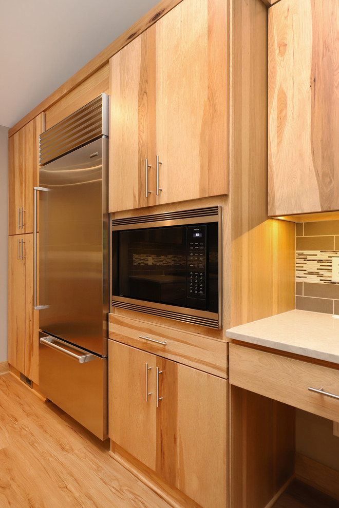 Example of a mid-sized transitional u-shaped light wood floor and brown floor eat-in kitchen design in Grand Rapids with an undermount sink, flat-panel cabinets, light wood cabinets, quartz countertops, brown backsplash, ceramic backsplash, stainless steel appliances and an island