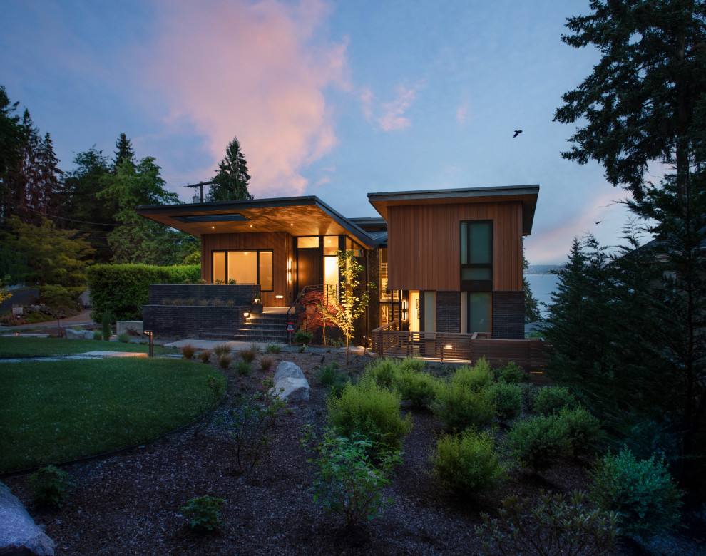 Идея дизайна: большой, деревянный, коричневый частный загородный дом в современном стиле с разными уровнями и крышей-бабочкой