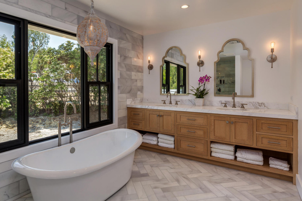 Design ideas for a large transitional master bathroom in Los Angeles with shaker cabinets, medium wood cabinets, a freestanding tub, gray tile, porcelain tile, marble floors, an undermount sink, marble benchtops, grey floor, grey benchtops, a double vanity and a built-in vanity.