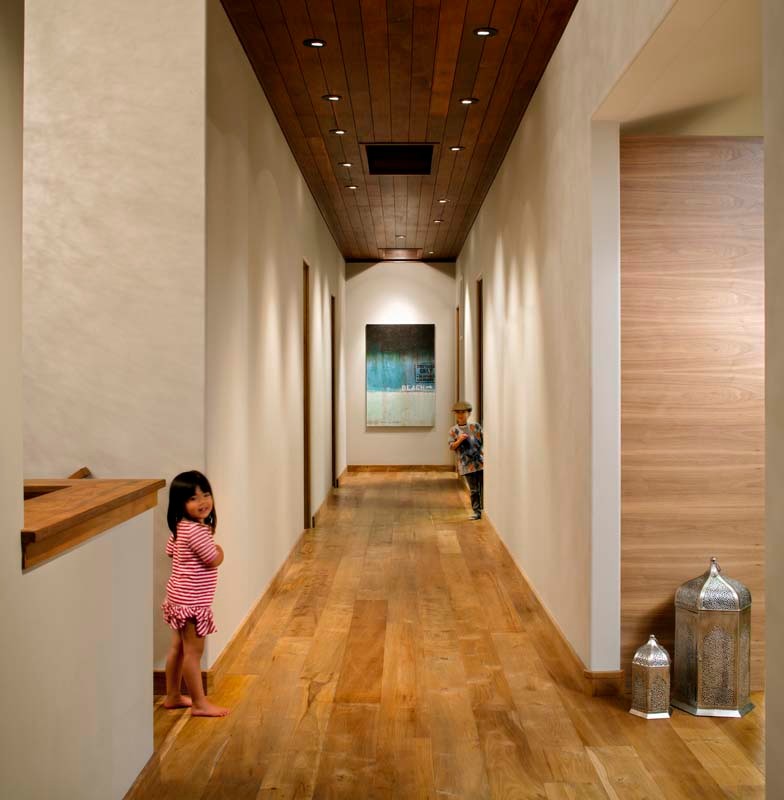 Photo of a large eclectic hallway in San Diego with beige walls and light hardwood floors.
