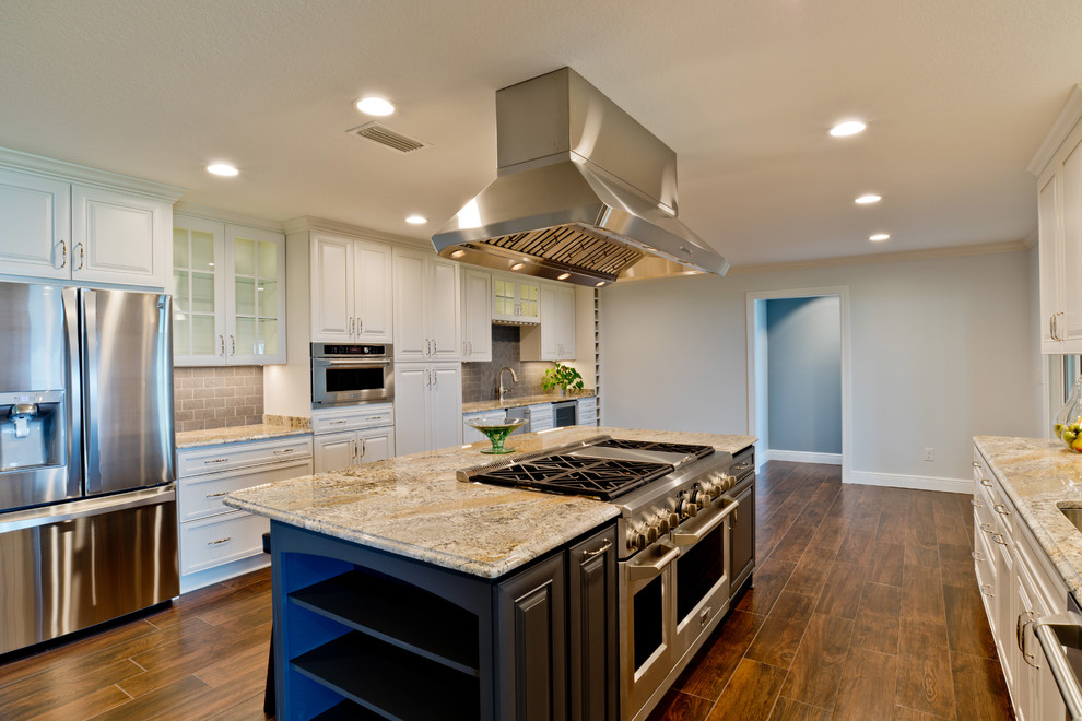 Example of a large transitional galley porcelain tile eat-in kitchen design in Miami with an undermount sink, raised-panel cabinets, white cabinets, granite countertops, gray backsplash, porcelain backsplash, stainless steel appliances and an island