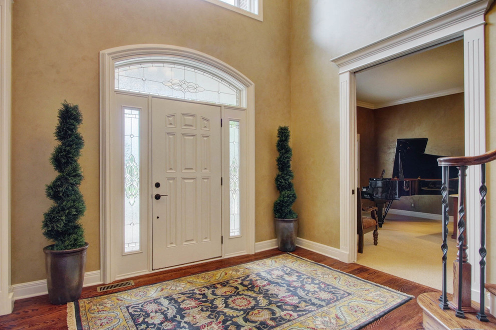Inspiration for a large transitional foyer in Kansas City with multi-coloured walls, dark hardwood floors, a single front door and a white front door.