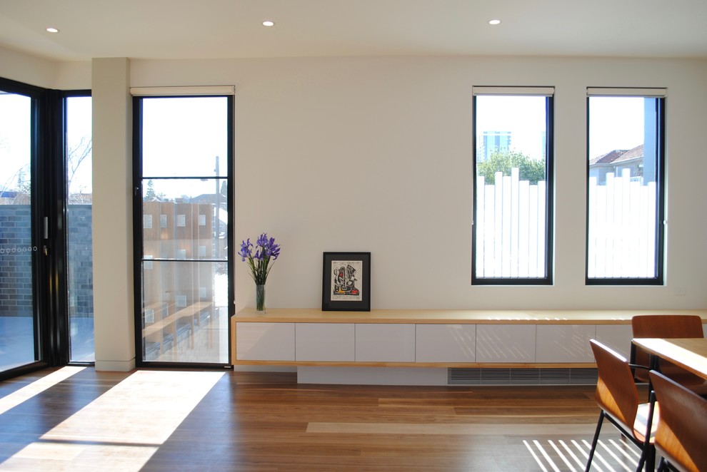 Photo of a small contemporary kitchen/dining combo in Melbourne with white walls, medium hardwood floors and no fireplace.
