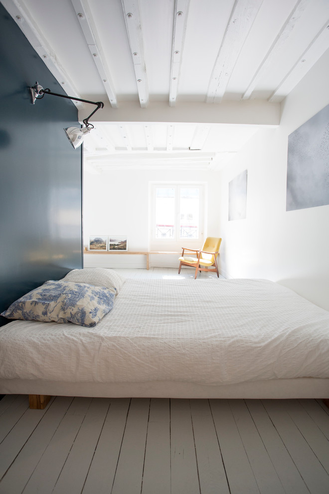 This is an example of a mid-sized scandinavian master bedroom in Paris with painted wood floors.