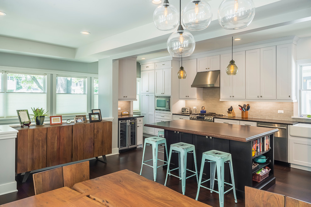 Inspiration for a mid-sized transitional l-shaped dark wood floor eat-in kitchen remodel in Chicago with a farmhouse sink, recessed-panel cabinets, white cabinets, laminate countertops, subway tile backsplash, stainless steel appliances and an island