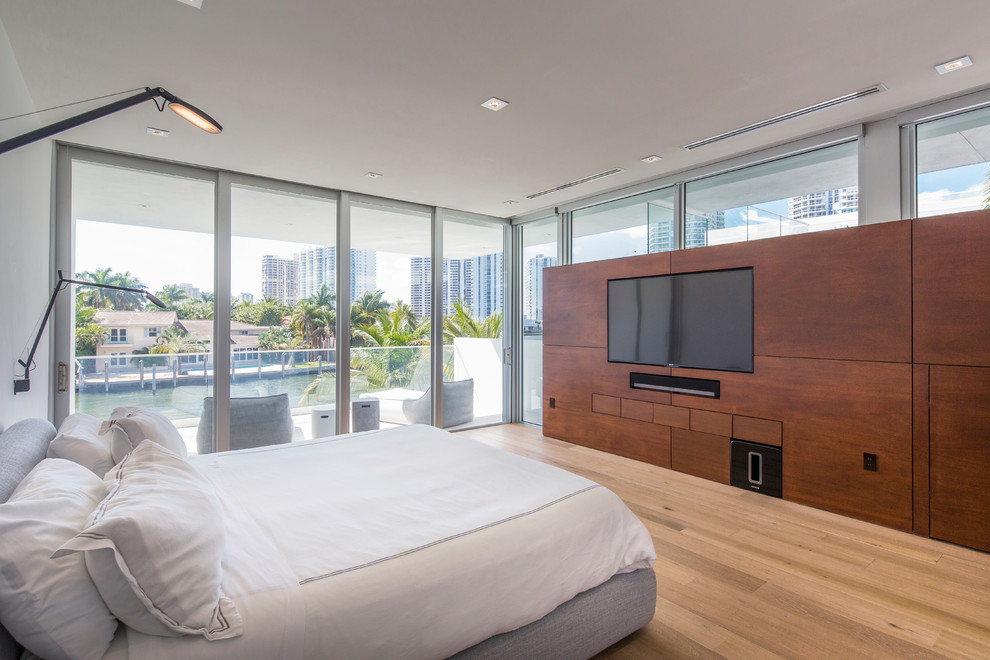 Photo of a contemporary bedroom in Miami with white walls, medium hardwood floors and brown floor.