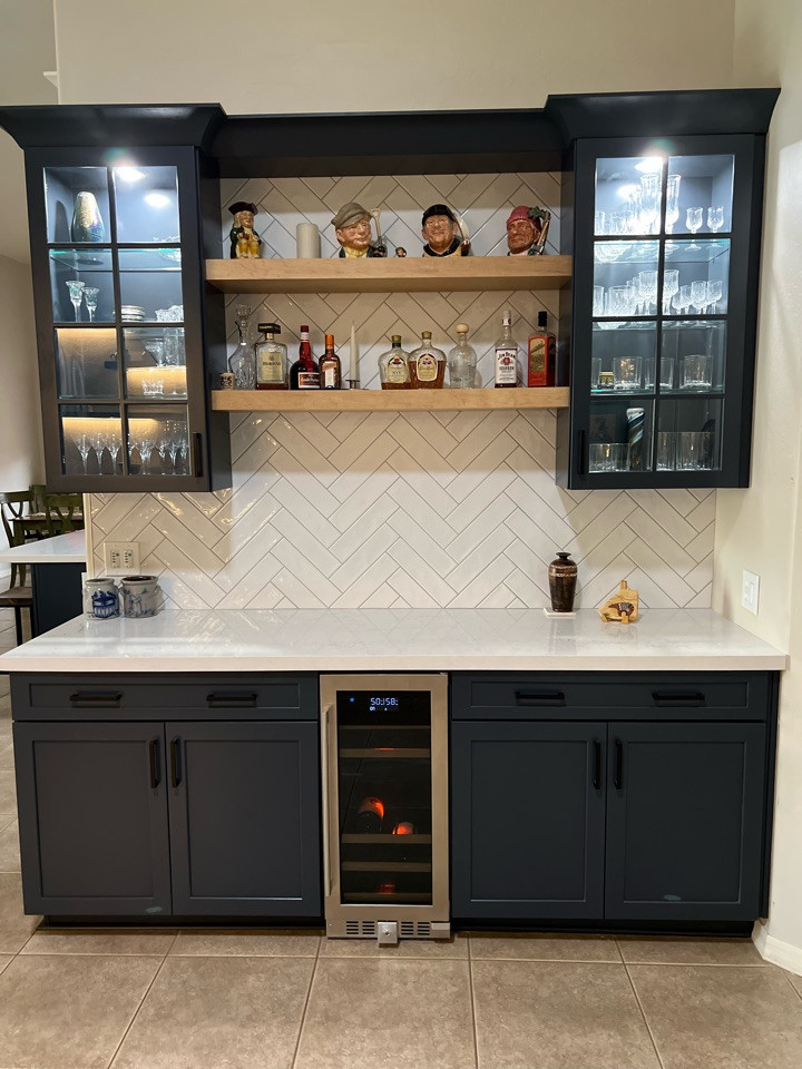 Photo of an expansive modern single-wall home bar in Phoenix with no sink, glass-front cabinets, blue cabinets, quartzite benchtops, white splashback, subway tile splashback and white benchtop.