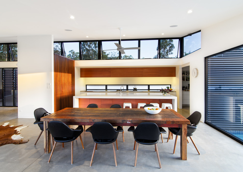 This is an example of a contemporary open plan dining in Sunshine Coast with white walls, concrete floors and no fireplace.
