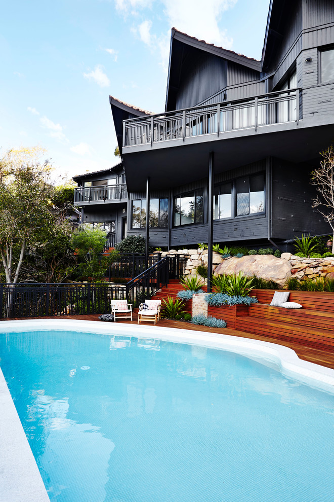 Mid-sized asian backyard custom-shaped pool in Sydney with decking.