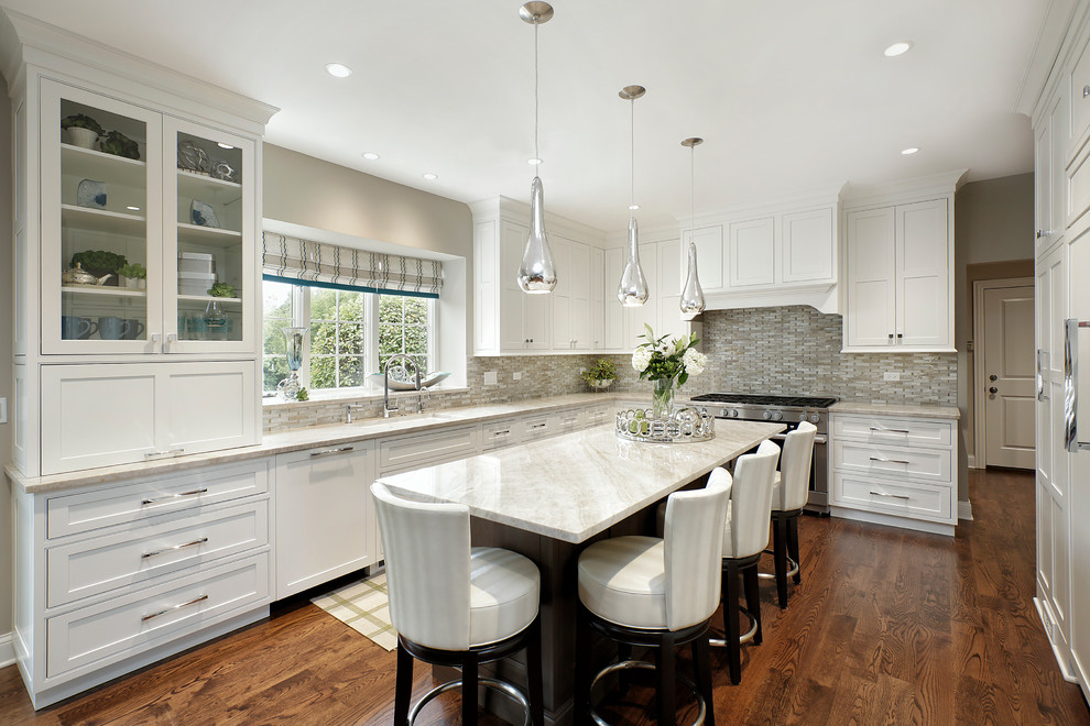Photo of a large transitional eat-in kitchen in Chicago with an undermount sink, recessed-panel cabinets, white cabinets, granite benchtops, beige splashback, glass tile splashback, stainless steel appliances, medium hardwood floors, with island and brown floor.