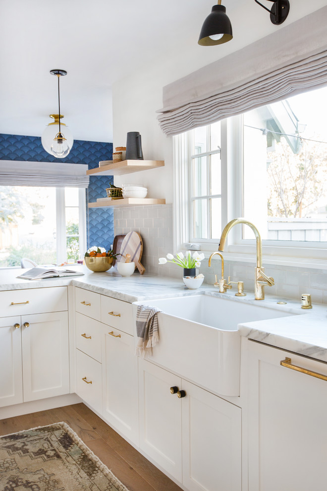 Inspiration for a mid-sized traditional galley separate kitchen in Los Angeles with a drop-in sink, recessed-panel cabinets, white cabinets, marble benchtops, grey splashback, ceramic splashback, stainless steel appliances, light hardwood floors, no island, beige floor and white benchtop.