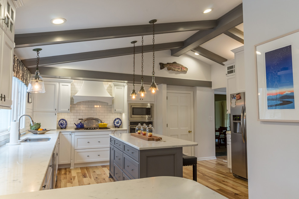 Large transitional u-shaped medium tone wood floor and brown floor enclosed kitchen photo with an undermount sink, shaker cabinets, white cabinets, quartzite countertops, white backsplash, subway tile backsplash, stainless steel appliances and an island