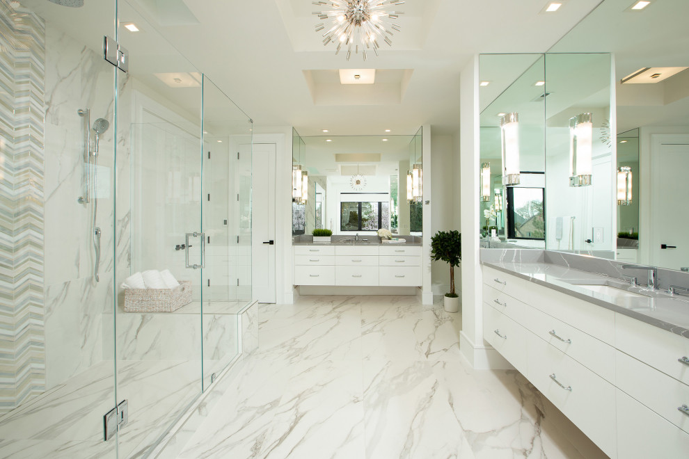 This is an example of an expansive transitional master bathroom in DC Metro with flat-panel cabinets, white cabinets, a freestanding tub, white tile, marble, marble floors, engineered quartz benchtops, a hinged shower door, grey benchtops, a shower seat, a single vanity, a floating vanity and recessed.