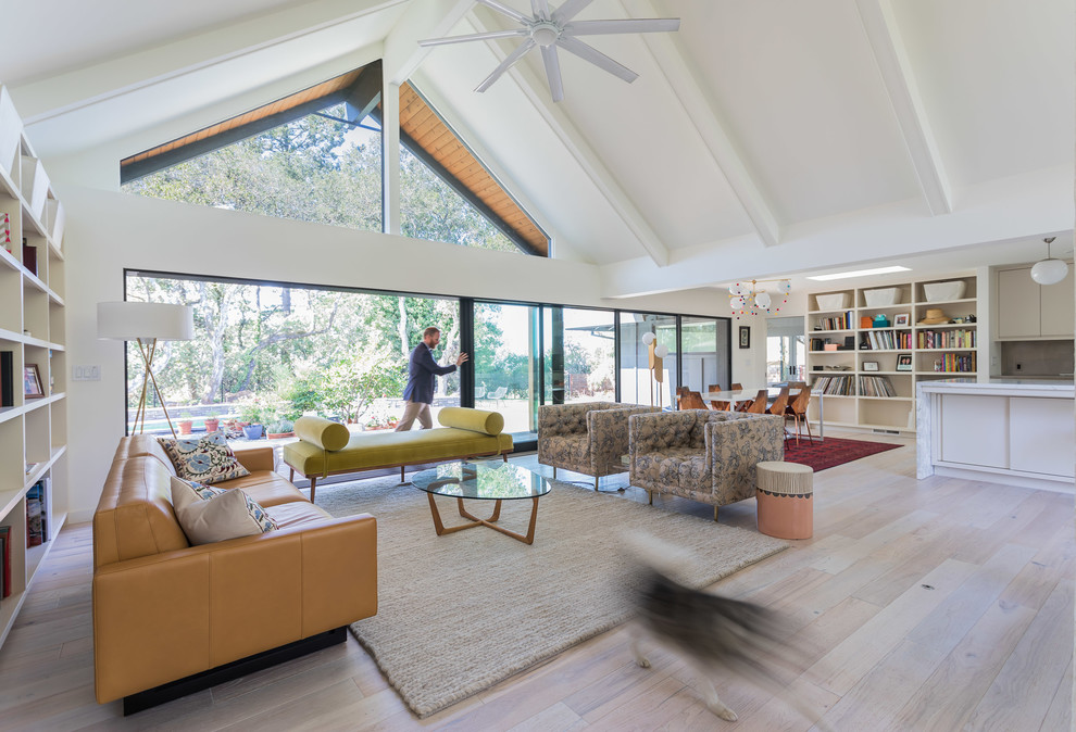 This is an example of a midcentury open concept living room in San Francisco with white walls, light hardwood floors, a two-sided fireplace and a plaster fireplace surround.