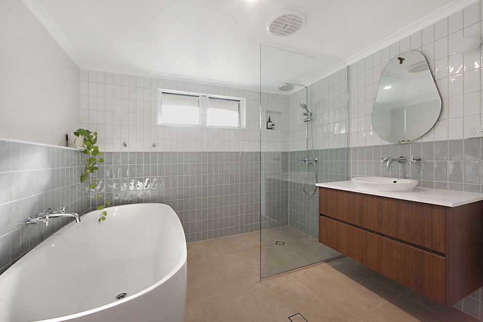 Inspiration for a mid-sized contemporary kids bathroom in Townsville with flat-panel cabinets, dark wood cabinets, a freestanding tub, an open shower, blue tile, ceramic tile, beige walls, porcelain floors, a drop-in sink, engineered quartz benchtops, beige floor and an open shower.