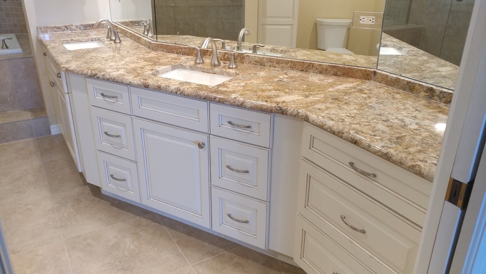 This is an example of a large traditional master bathroom in Tampa with raised-panel cabinets, white cabinets, a drop-in tub, an open shower, a two-piece toilet, beige tile, porcelain tile, beige walls, porcelain floors, an undermount sink, granite benchtops, beige floor and a hinged shower door.