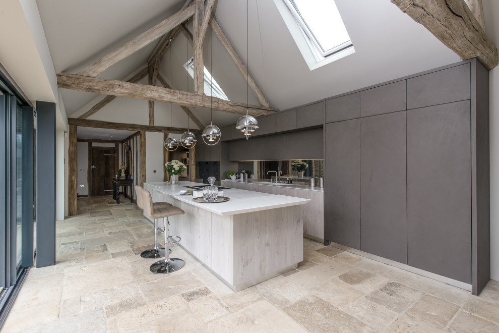 This is an example of a large country galley kitchen in Surrey with flat-panel cabinets, grey cabinets, quartzite benchtops, metallic splashback, with island, white benchtop, mirror splashback and beige floor.