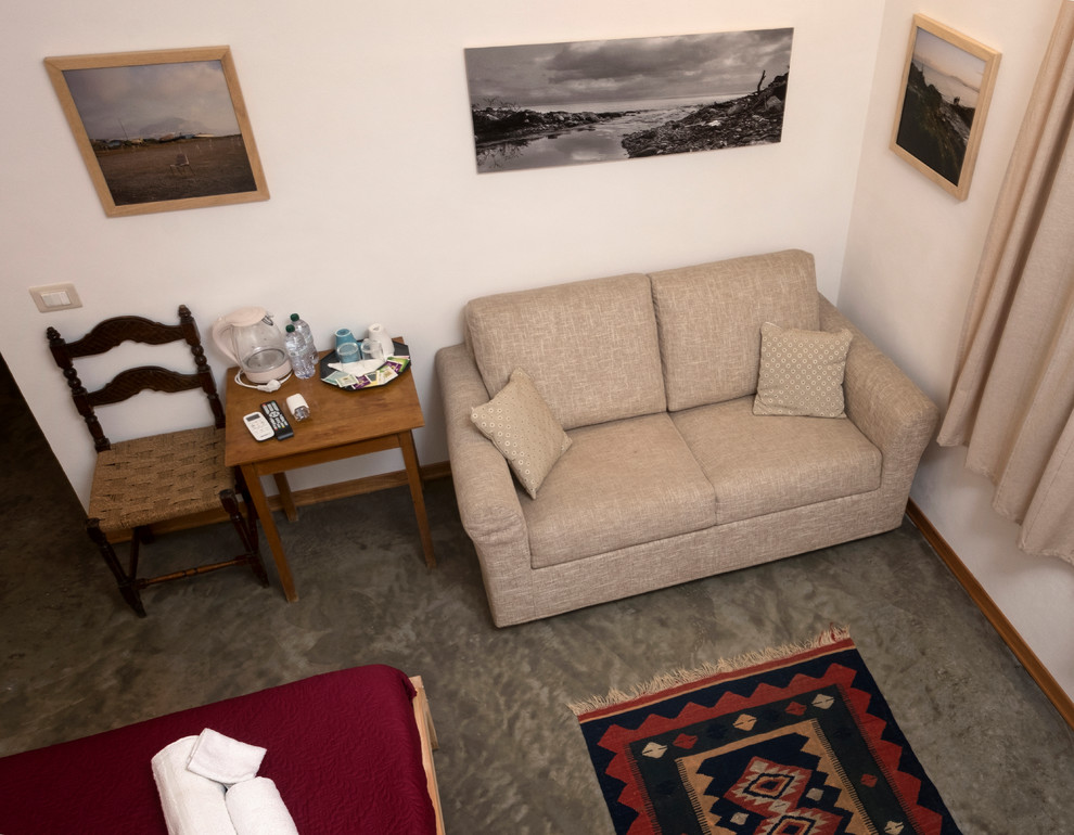 Foto di una camera degli ospiti mediterranea di medie dimensioni con pareti bianche, pavimento in cemento e pavimento grigio