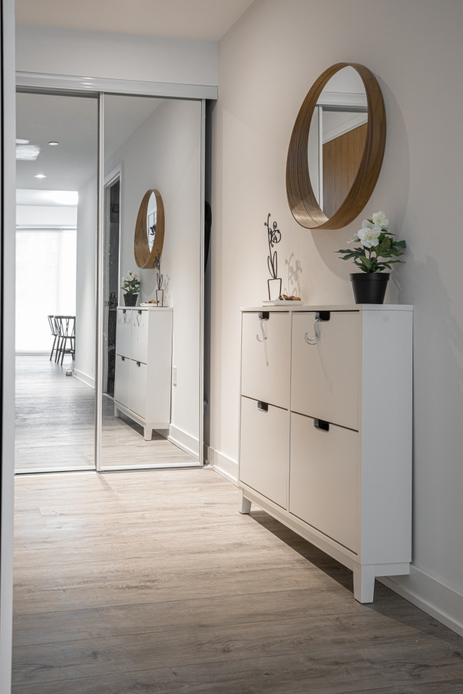 This is an example of a small scandi foyer in Toronto with white walls, laminate floors, a single front door, a white front door and brown floors.