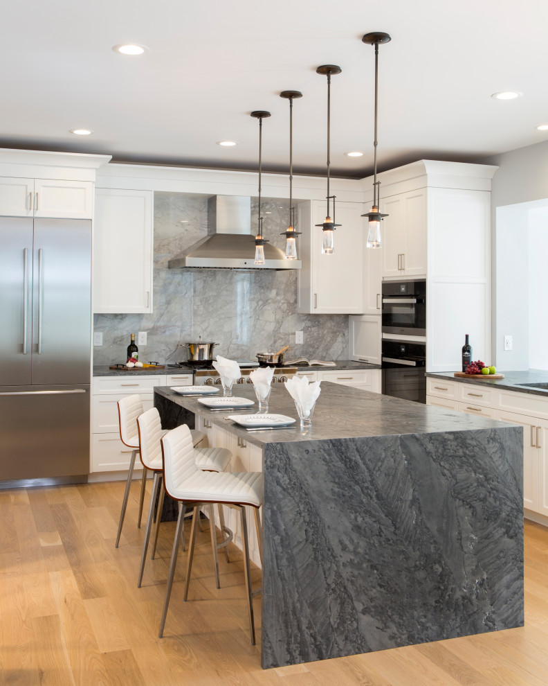Photo of a large transitional kitchen in Philadelphia with an undermount sink, shaker cabinets, white cabinets, quartzite benchtops, grey splashback, porcelain splashback, stainless steel appliances, light hardwood floors, with island, beige floor and grey benchtop.
