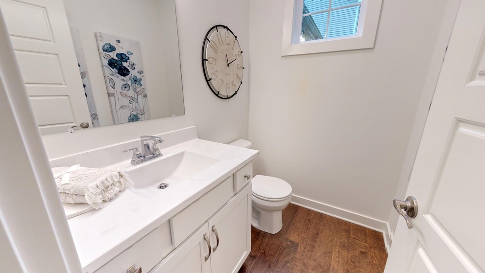 Photo of a large arts and crafts powder room in Louisville with recessed-panel cabinets, grey cabinets, a one-piece toilet, white tile, subway tile, white walls, ceramic floors, an integrated sink, marble benchtops, grey floor and white benchtops.