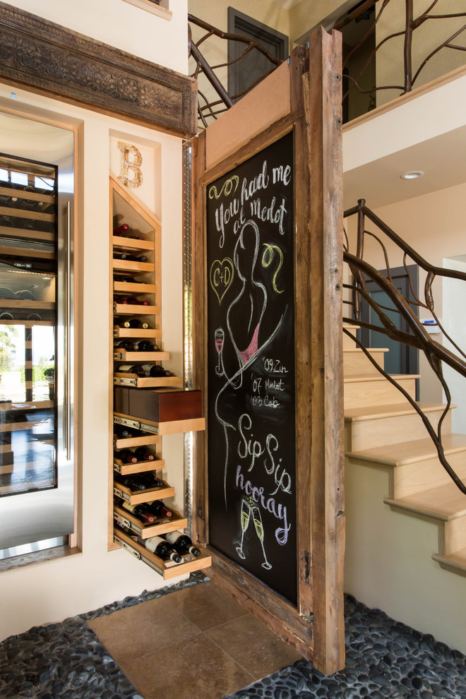 Large eclectic wine cellar in Los Angeles with travertine floors and storage racks.