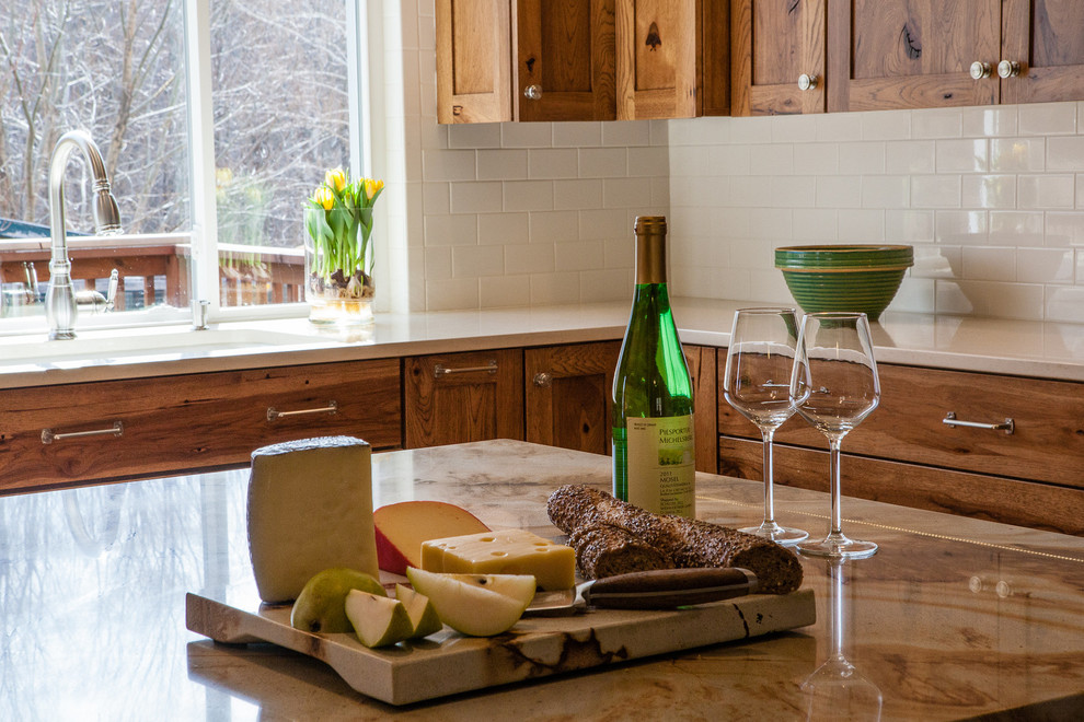 Mid-sized mountain style l-shaped light wood floor kitchen photo in Indianapolis with a single-bowl sink, flat-panel cabinets, medium tone wood cabinets, quartzite countertops, white backsplash, subway tile backsplash, paneled appliances, white walls and an island