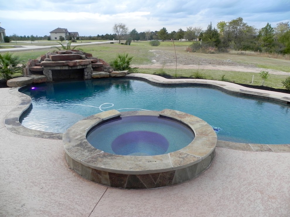 Mid-sized country backyard custom-shaped pool in Houston with a hot tub and tile.