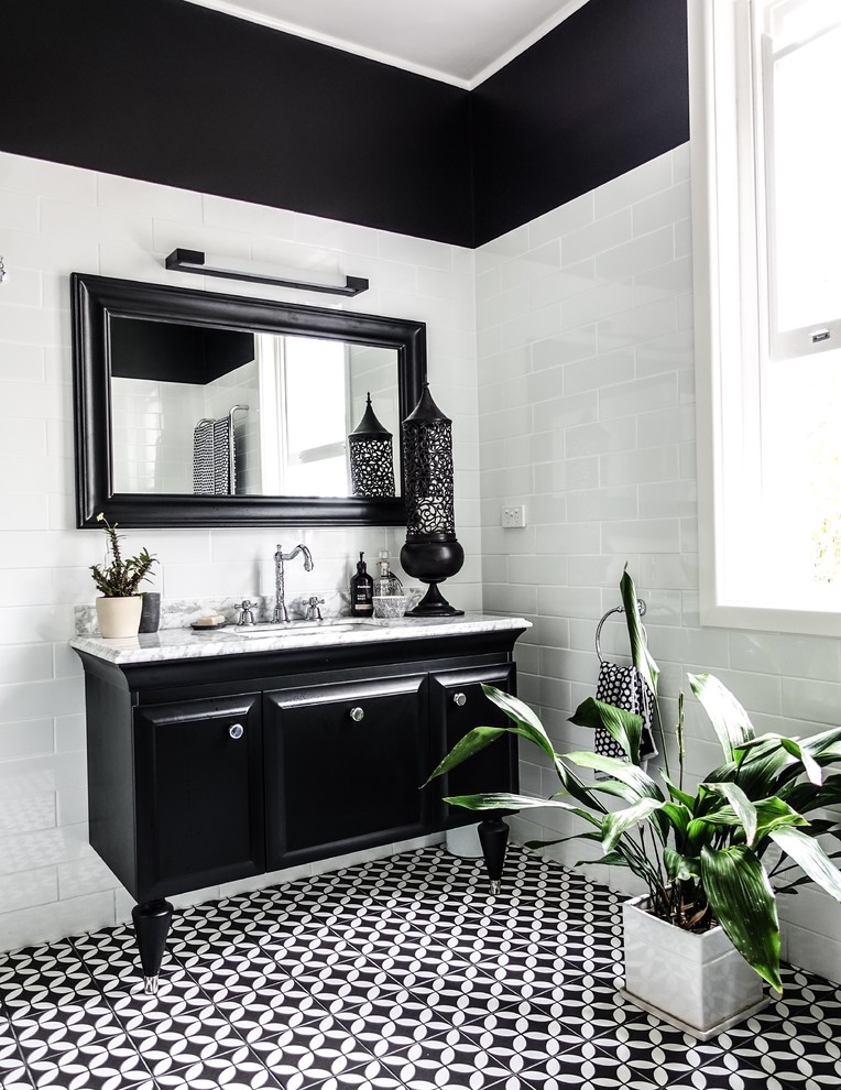 This is an example of a large country master bathroom in Sydney with raised-panel cabinets, black cabinets, a freestanding tub, a corner shower, a one-piece toilet, white tile, ceramic tile, black walls, ceramic floors, a drop-in sink, marble benchtops, black floor, a hinged shower door and white benchtops.