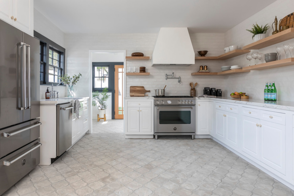 Example of a transitional u-shaped gray floor kitchen design in Los Angeles with a farmhouse sink, raised-panel cabinets, white cabinets, white backsplash, stainless steel appliances, no island and white countertops