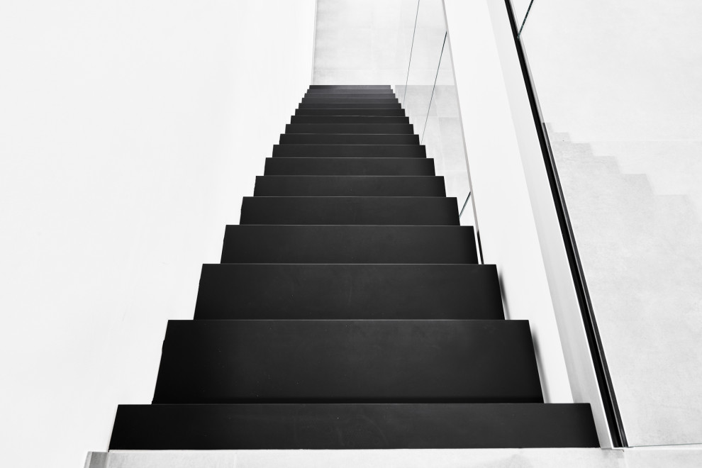 Консольная лестница в черном матовом цвете с ограждением из белого стекла