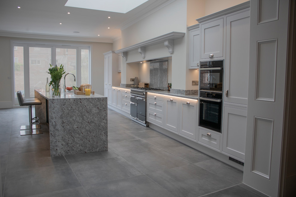 Design ideas for a large traditional single-wall eat-in kitchen in Devon with an integrated sink, white cabinets, granite benchtops, grey splashback, black appliances, slate floors, with island, grey floor and grey benchtop.