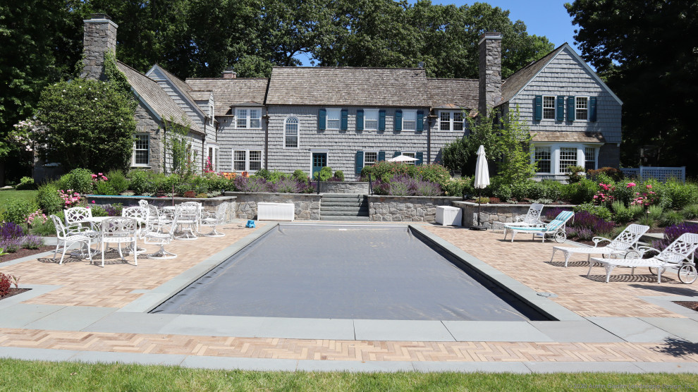 Diseño de piscina tradicional de tamaño medio rectangular en patio trasero con paisajismo de piscina y adoquines de ladrillo