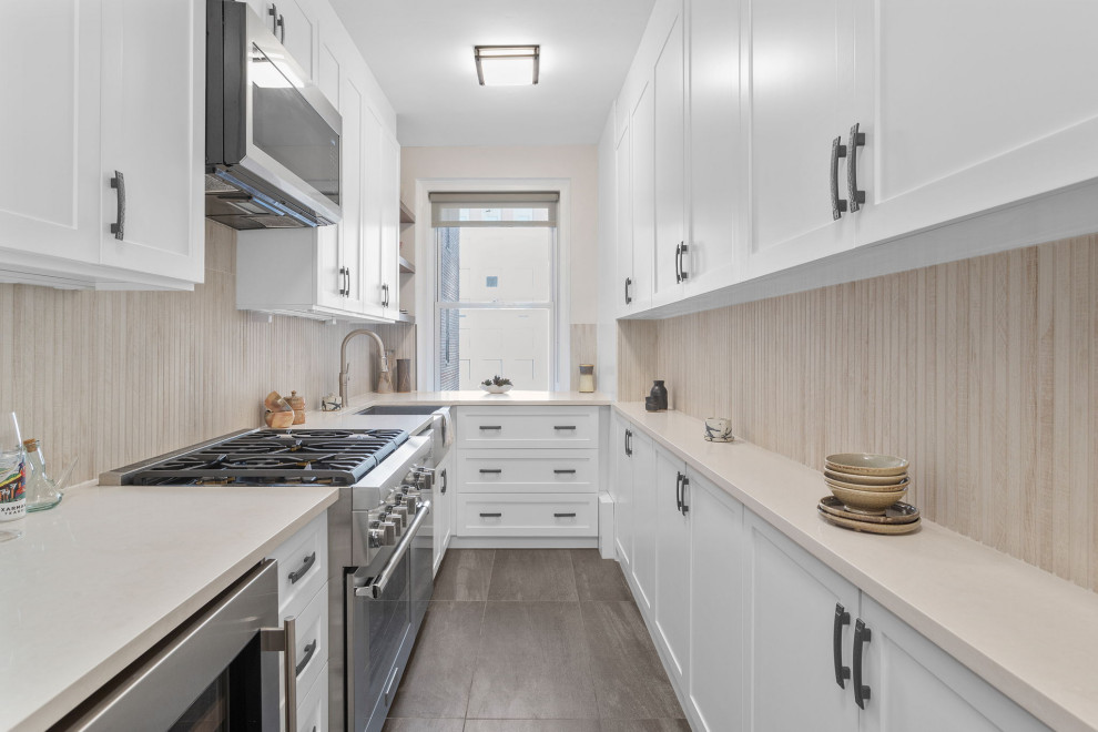 This is an example of a medium sized scandi galley enclosed kitchen in New York with a submerged sink, shaker cabinets, white cabinets, engineered stone countertops, beige splashback, ceramic splashback, stainless steel appliances, ceramic flooring, grey floors and beige worktops.