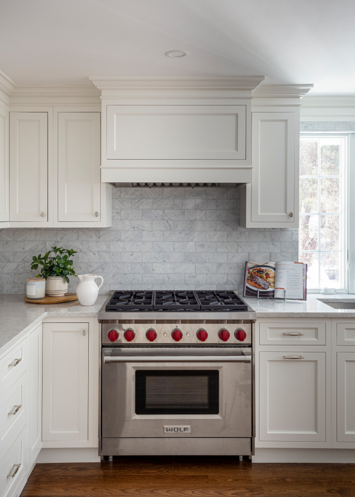 Inspiration for a traditional kitchen in Boston with a submerged sink, beaded cabinets, white cabinets, engineered stone countertops, white splashback, marble splashback, stainless steel appliances, medium hardwood flooring, brown floors and white worktops.