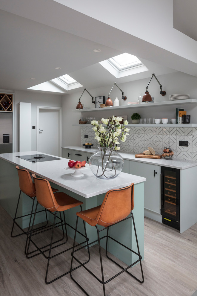 Photo of a mid-sized contemporary single-wall kitchen in Gloucestershire with an undermount sink, flat-panel cabinets, with island, grey floor and white benchtop.