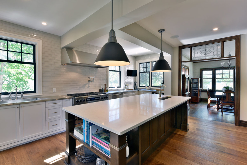 Eat-in kitchen - mid-sized transitional galley medium tone wood floor eat-in kitchen idea in Ottawa with an undermount sink, shaker cabinets, white cabinets, solid surface countertops, white backsplash, stainless steel appliances, an island and subway tile backsplash
