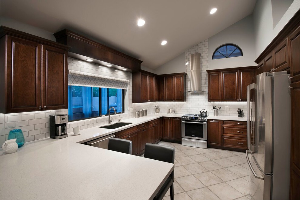 Inspiration for a large transitional u-shaped ceramic tile eat-in kitchen remodel in Phoenix with an undermount sink, raised-panel cabinets, dark wood cabinets, quartz countertops, white backsplash, subway tile backsplash, stainless steel appliances and a peninsula