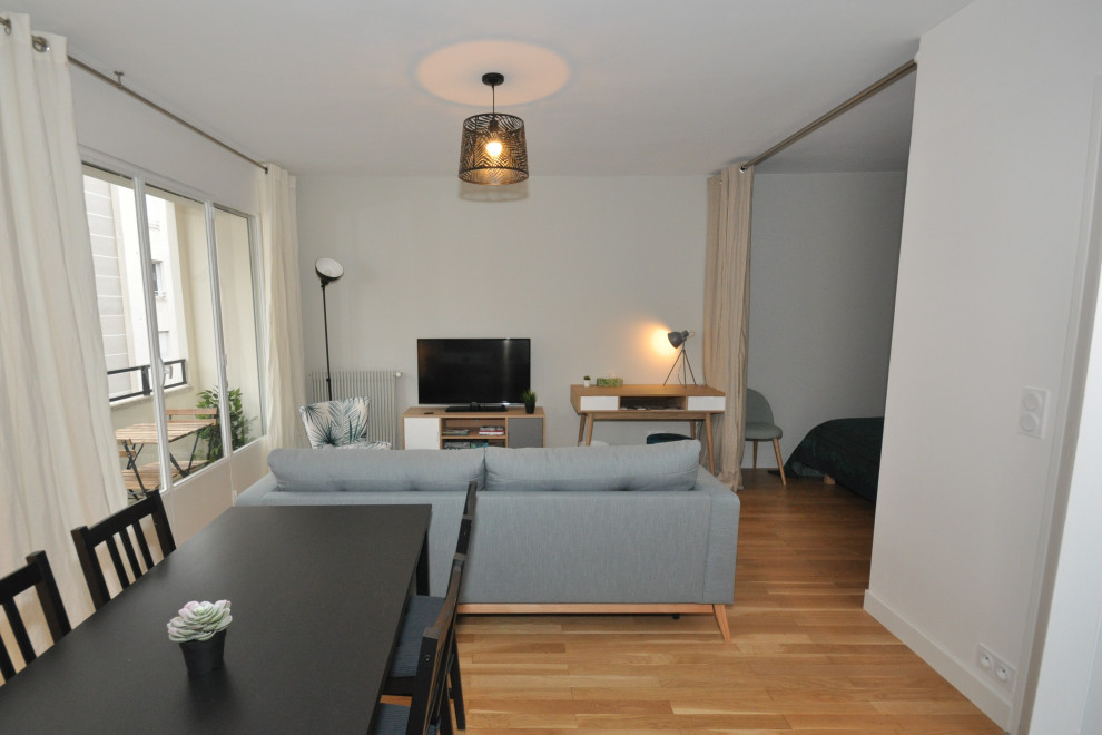 Immagine di un soggiorno nordico di medie dimensioni con TV autoportante, pareti bianche, pavimento in legno massello medio e pavimento marrone