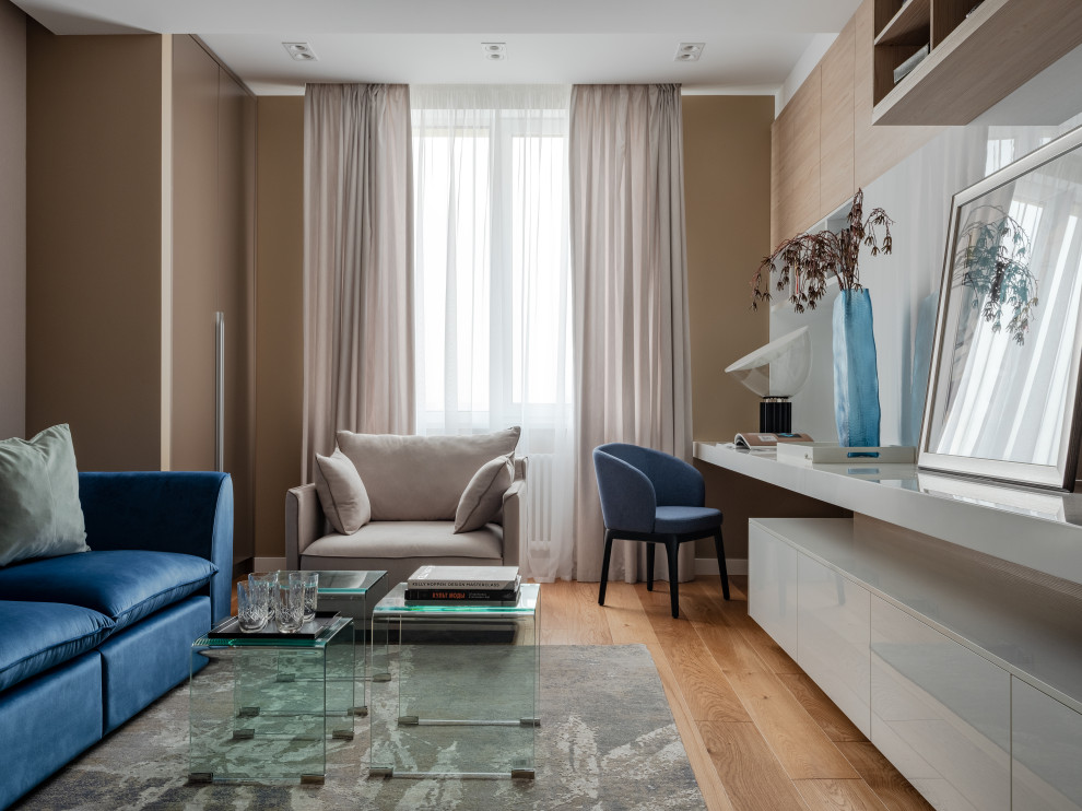 Ejemplo de despacho actual con paredes beige, suelo de madera en tonos medios y panelado