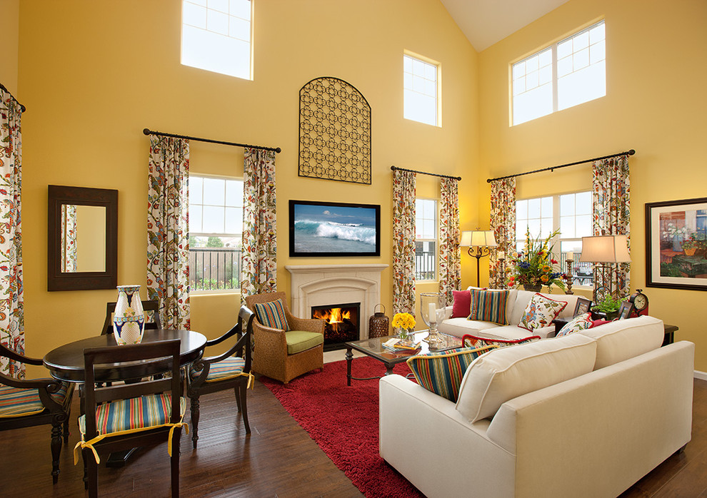 Expansive mediterranean living room in Santa Barbara with yellow walls, dark hardwood floors, a standard fireplace, a stone fireplace surround and a wall-mounted tv.