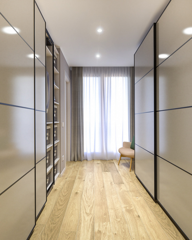Mid-sized scandinavian gender-neutral walk-in wardrobe in Milan with flat-panel cabinets, beige cabinets, light hardwood floors and recessed.