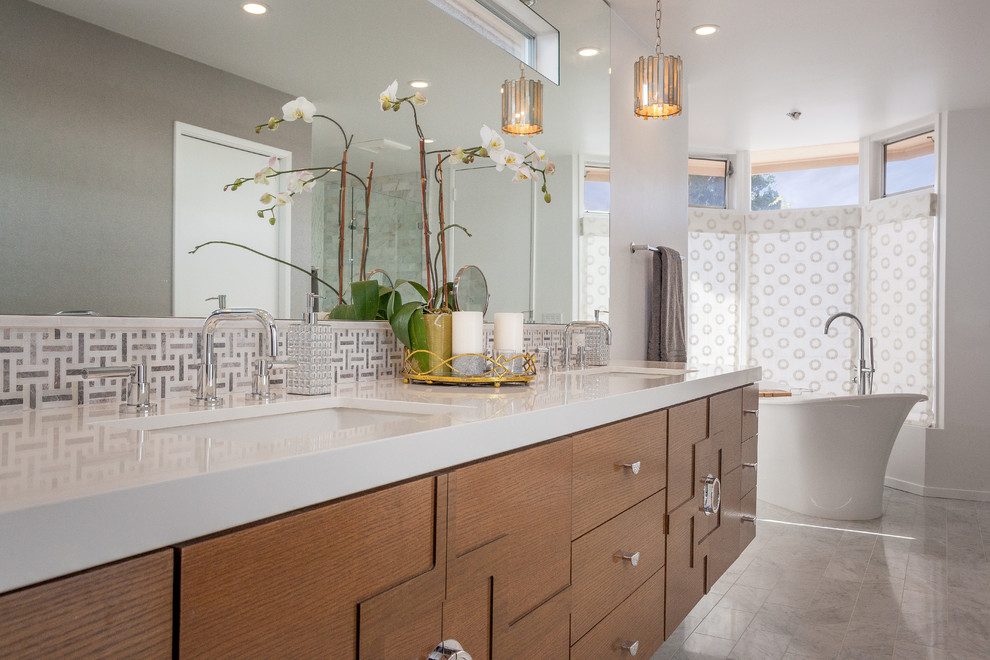 Inspiration for a large contemporary master bathroom in Orange County with furniture-like cabinets, medium wood cabinets, a freestanding tub, a double shower, a one-piece toilet, gray tile, stone tile, white walls, marble floors, an undermount sink and engineered quartz benchtops.