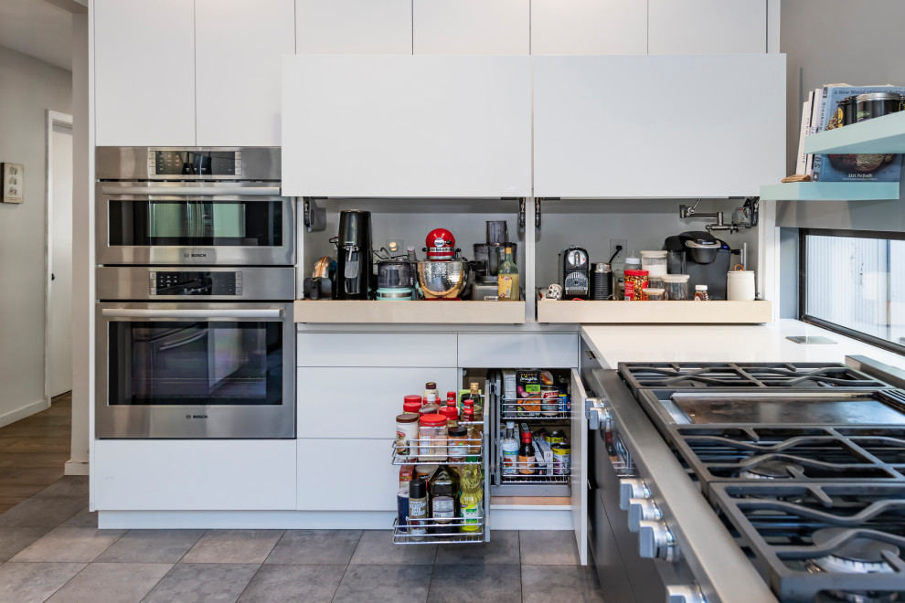 This is an example of a mid-sized modern l-shaped kitchen pantry in San Francisco with a single-bowl sink, flat-panel cabinets, grey cabinets, quartz benchtops, white splashback, engineered quartz splashback, stainless steel appliances, ceramic floors, grey floor and white benchtop.