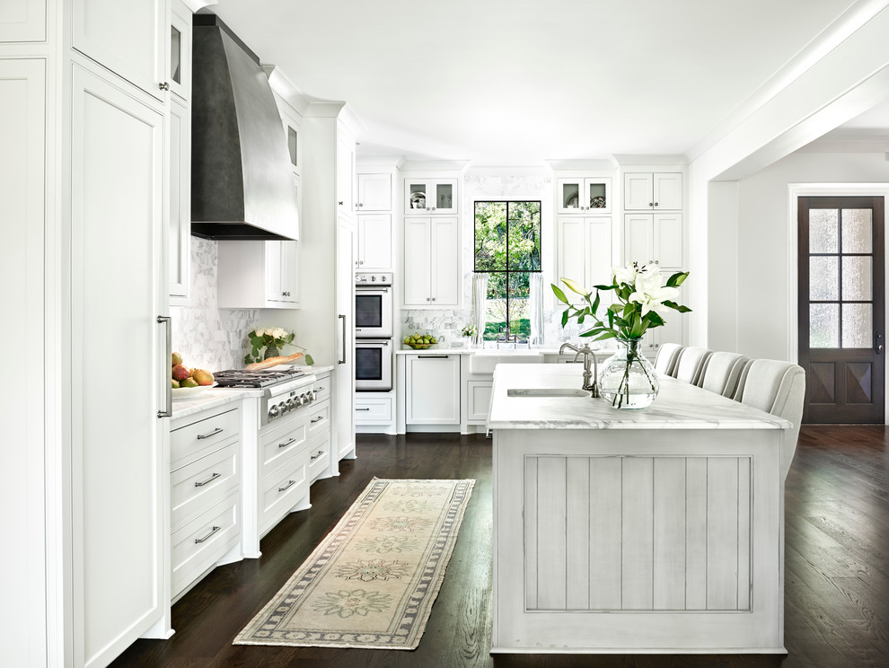 Design ideas for a mid-sized transitional u-shaped eat-in kitchen in Nashville with a farmhouse sink, white cabinets, white splashback, stone tile splashback, stainless steel appliances, medium hardwood floors and with island.